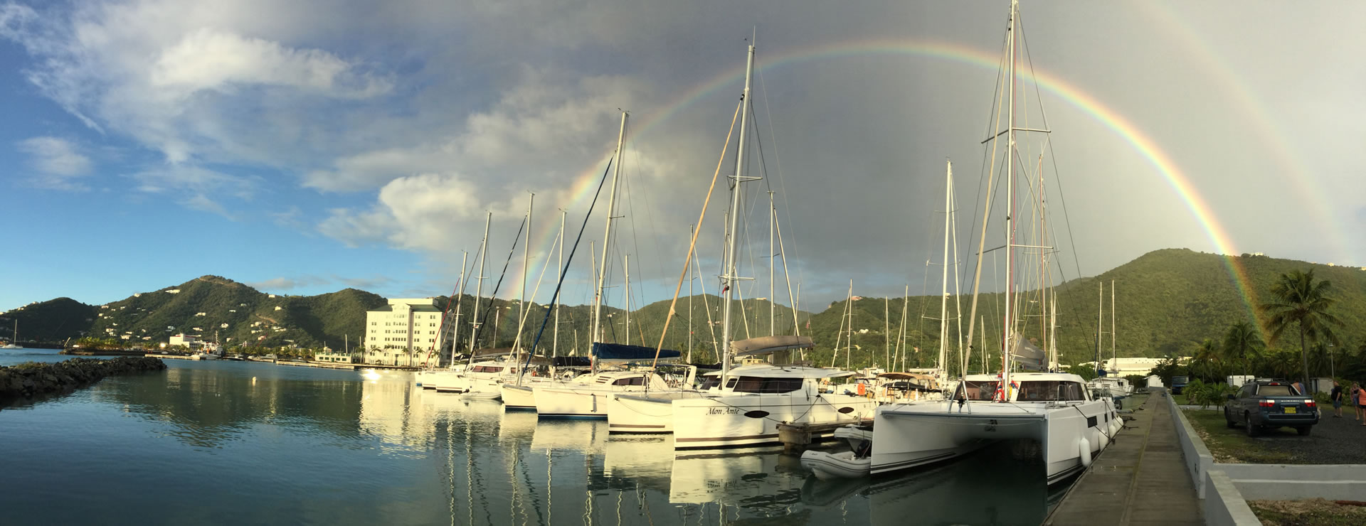 BVI Yacht Charters fleet at the marina beneath a rainbow